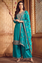 Model wearing turquoise blue art silk palazzo suit with scalloped dupatta