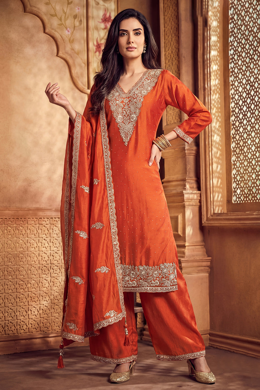 Model wearing orange art silk palazzo suit with scalloped embroidery dupatta