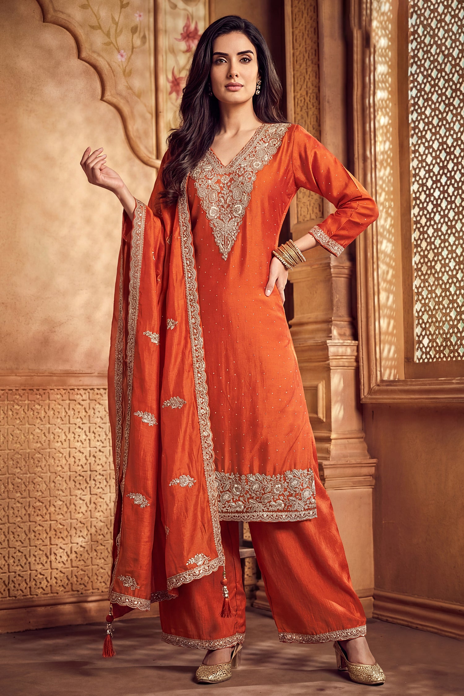 Model wearing orange art silk palazzo suit with scalloped embroidery dupatta