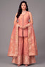 Woman wearing a traditional peach embroidered outfit on a gray background