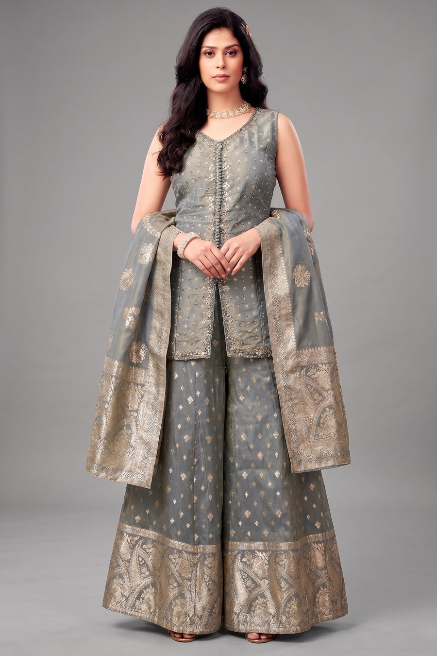 Woman wearing a traditional outfit with a gray and gold color scheme on a gray background